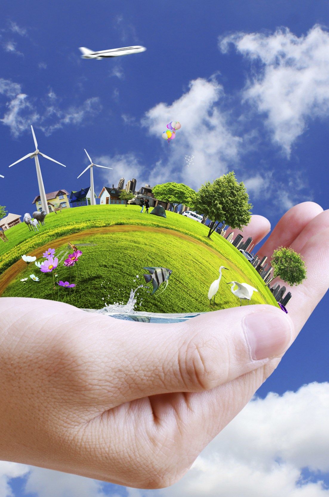 A hand holding a small green world with wind turbines and trees